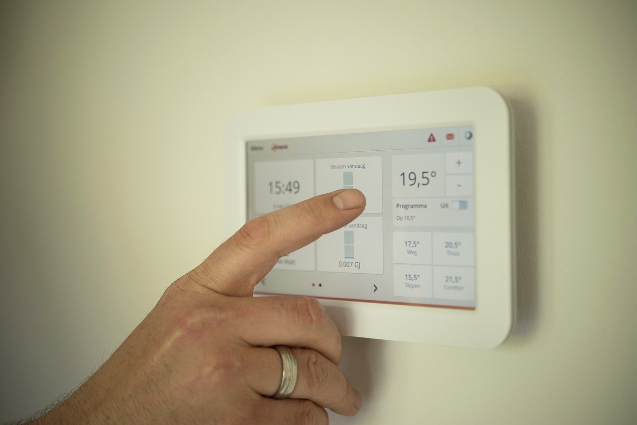 Hand stellt ein digitales Thermostat auf 19,5 Grad